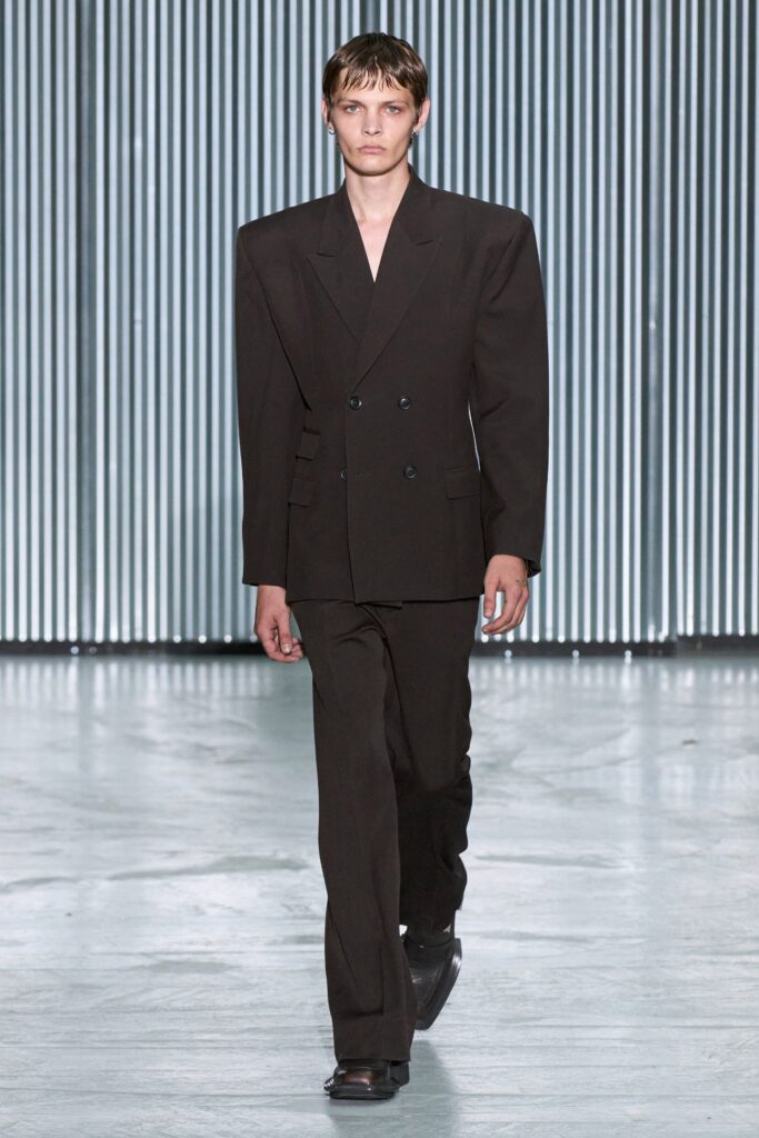 A tailored black wool suit featuring long sleeves and a buttoned design with straight-leg trousers.