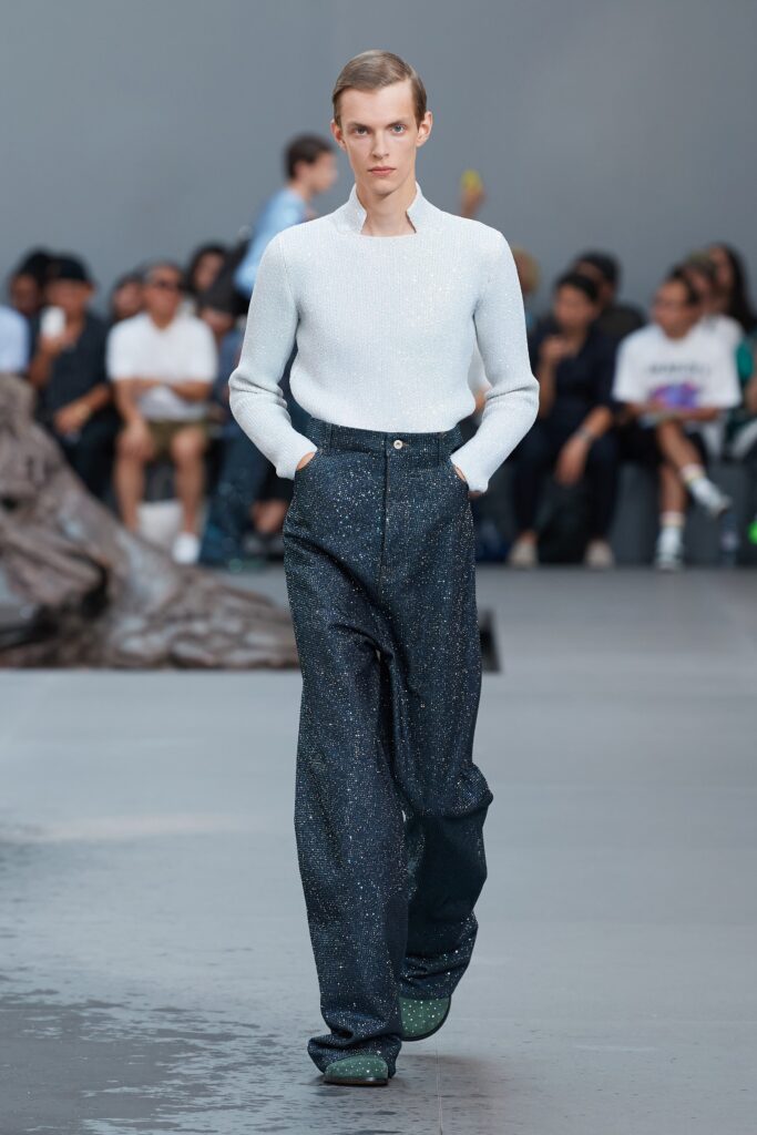A relaxed white long-sleeve cotton sweater paired with wide-leg black denim pants.