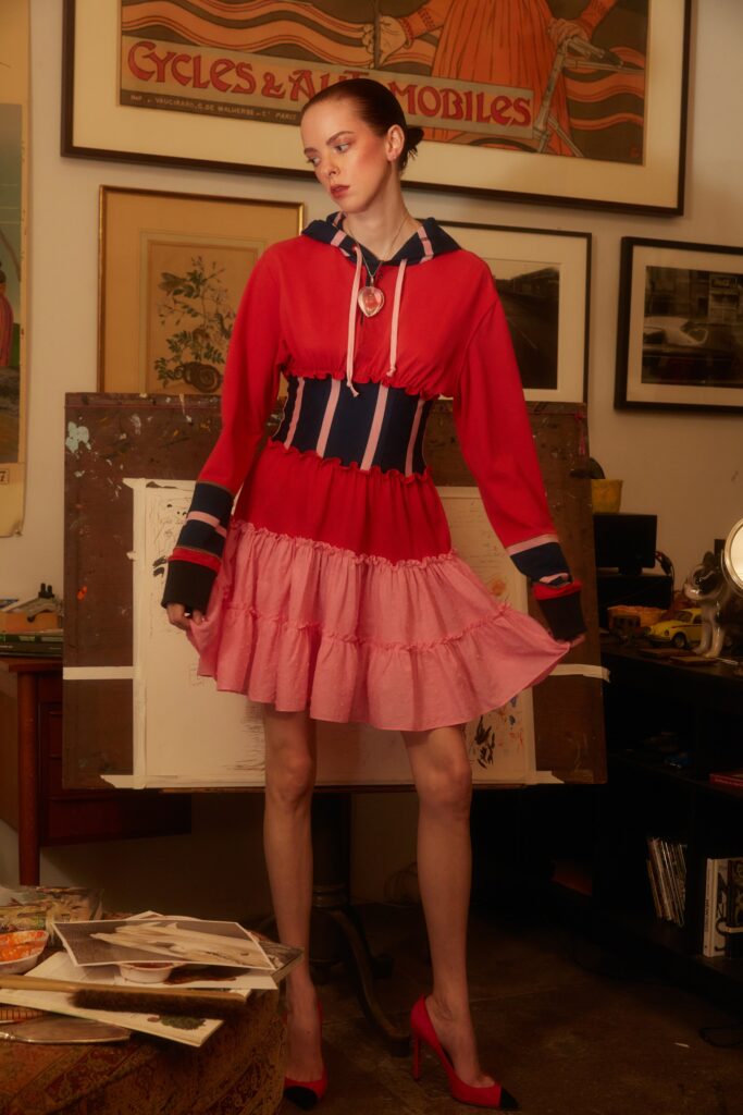 A fitted red and pink cotton dress with long sleeves, a collared neckline, and a tiered design.