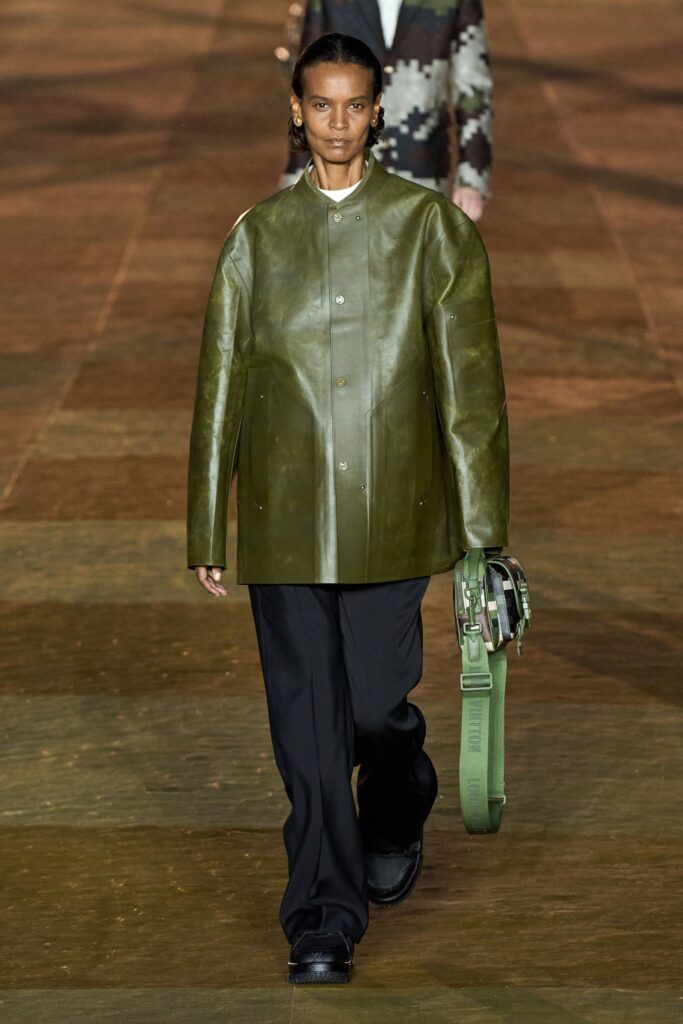 An oversized green leather jacket paired with black pants, featuring a collared design and buttoned closure.