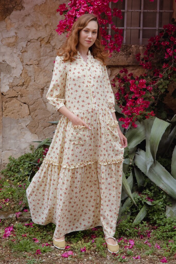A relaxed cream cotton dress with long sleeves, a collared neckline, and a tiered design.