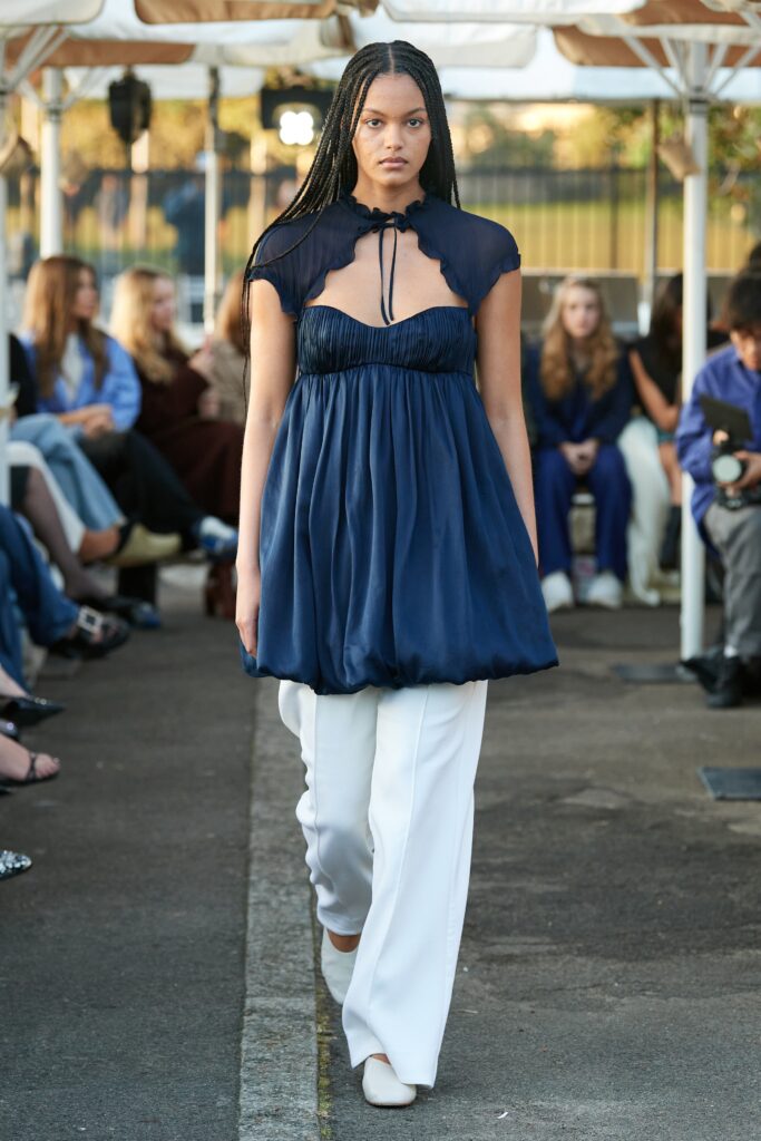 A relaxed blue silk sleeveless top with a V-neck and layered design, paired with white pants.