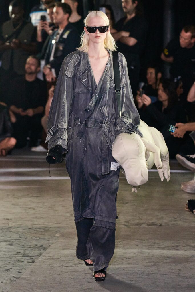 A relaxed gray denim jumpsuit with long sleeves and a V-neckline featuring a zippered detail.