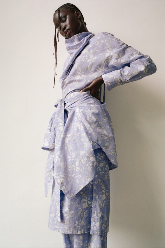 A relaxed blue cotton dress with long sleeves and a V-neckline featuring a flared silhouette.