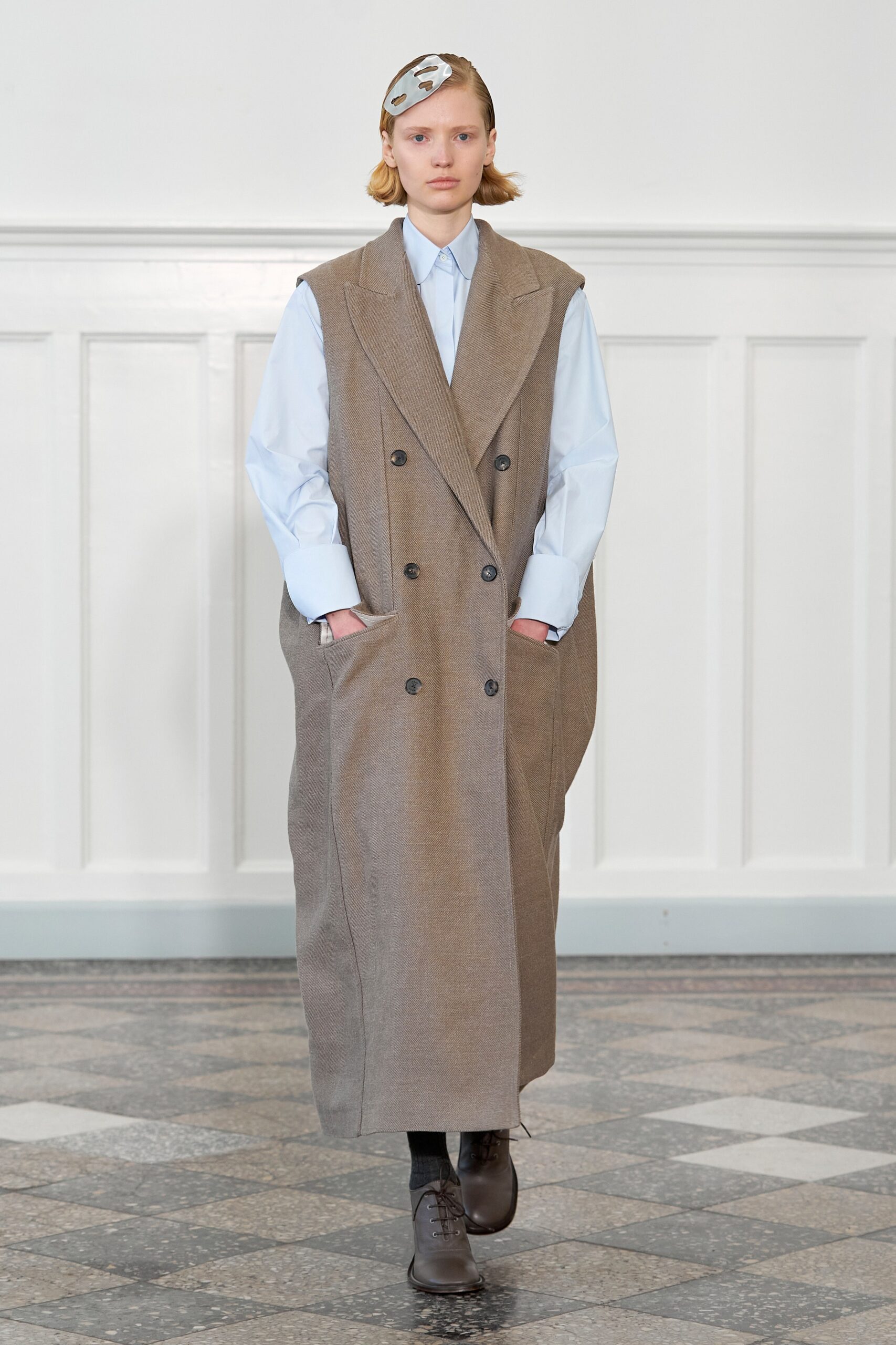 An oversized brown wool coat with long sleeves and a collared design featuring button details.