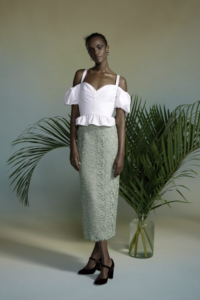 A fitted pink cotton top with short sleeves paired with a pleated green lace skirt.