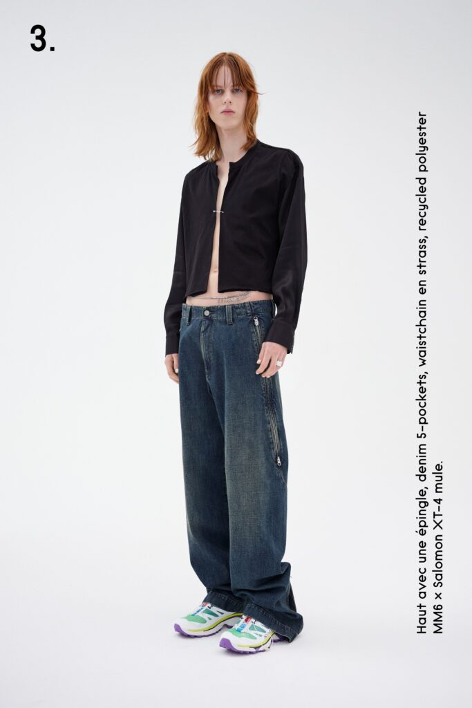 A relaxed black jacket paired with wide-leg blue denim pants, featuring a zippered detail.