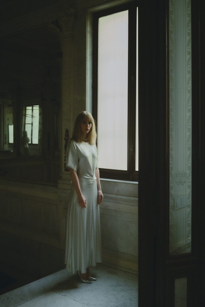 A relaxed white silk dress with short sleeves and a V-neckline featuring a tiered design.