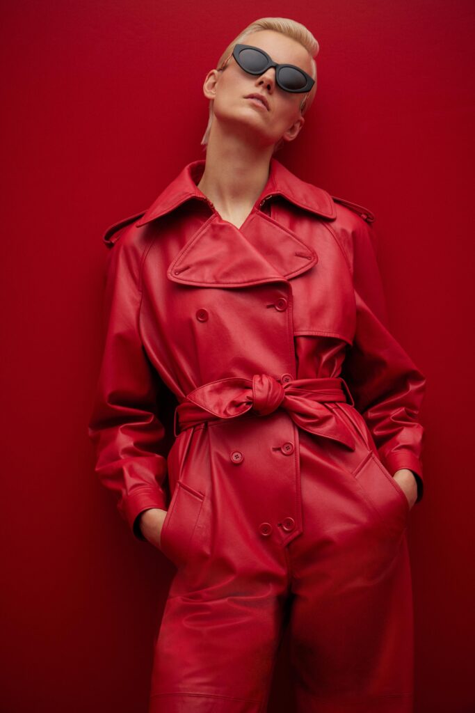 A fitted red leather jacket with a belted waist and collared design.