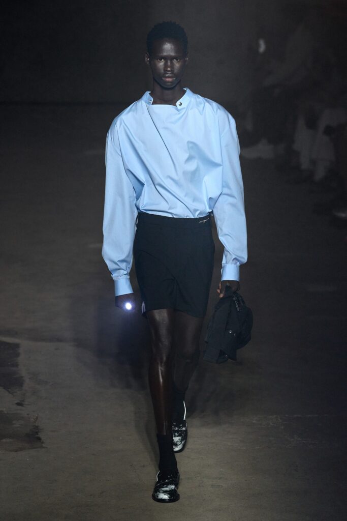 A relaxed blue long-sleeve shirt with a collared neckline paired with black shorts.