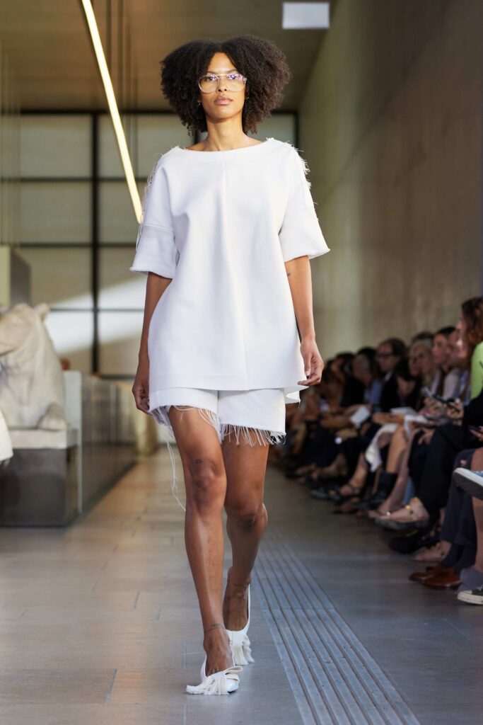 An oversized white cotton top paired with fringed white shorts for a chic summer look.