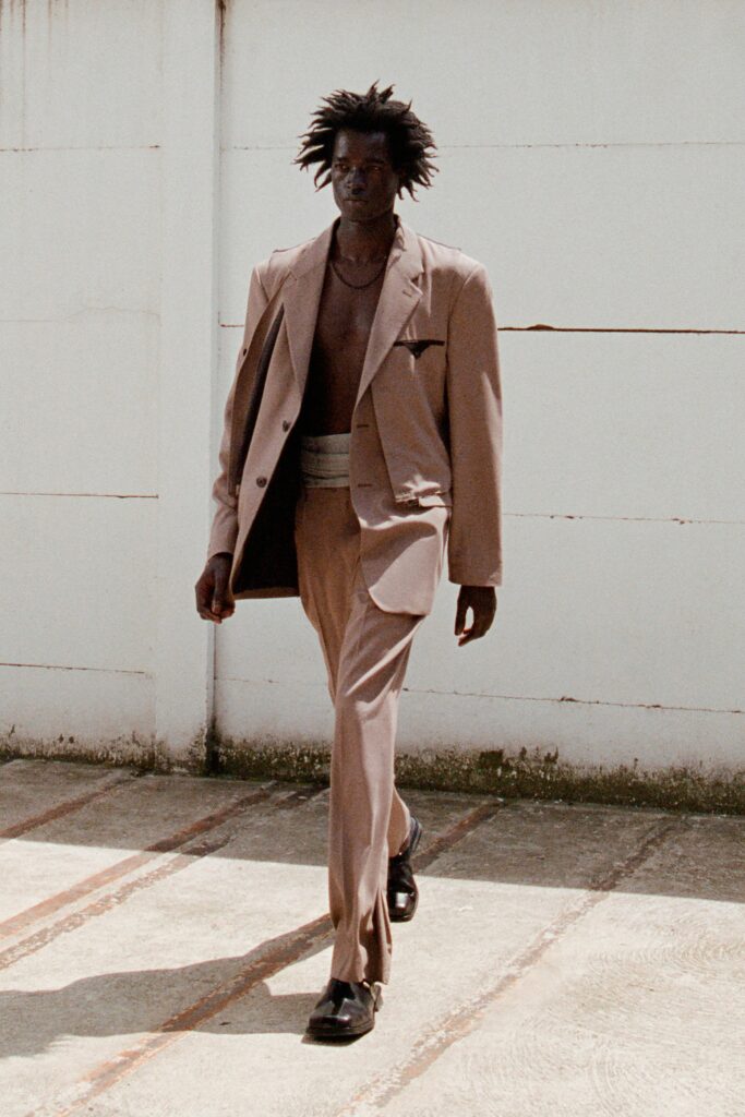 A tailored beige suit featuring a collared long-sleeve jacket and buttoned details.