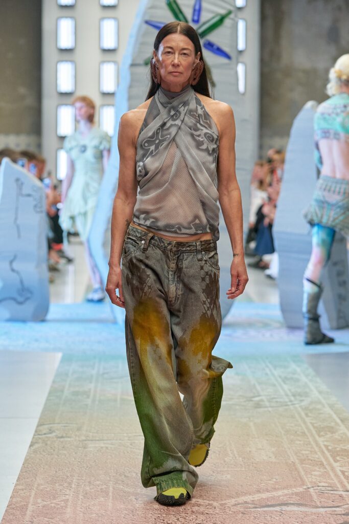 A relaxed gray mesh sleeveless top paired with wide-leg printed pants in green and orange hues.