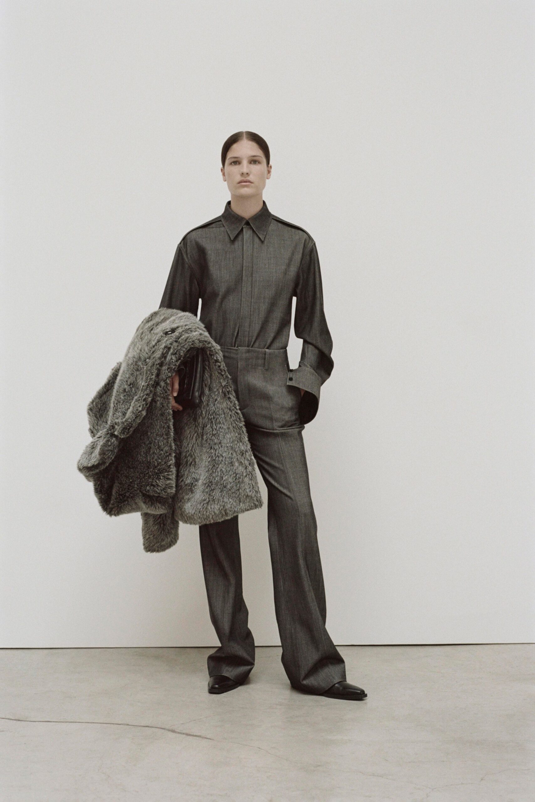 A fitted gray wool jacket with long sleeves and collared design, paired with straight-leg pants.
