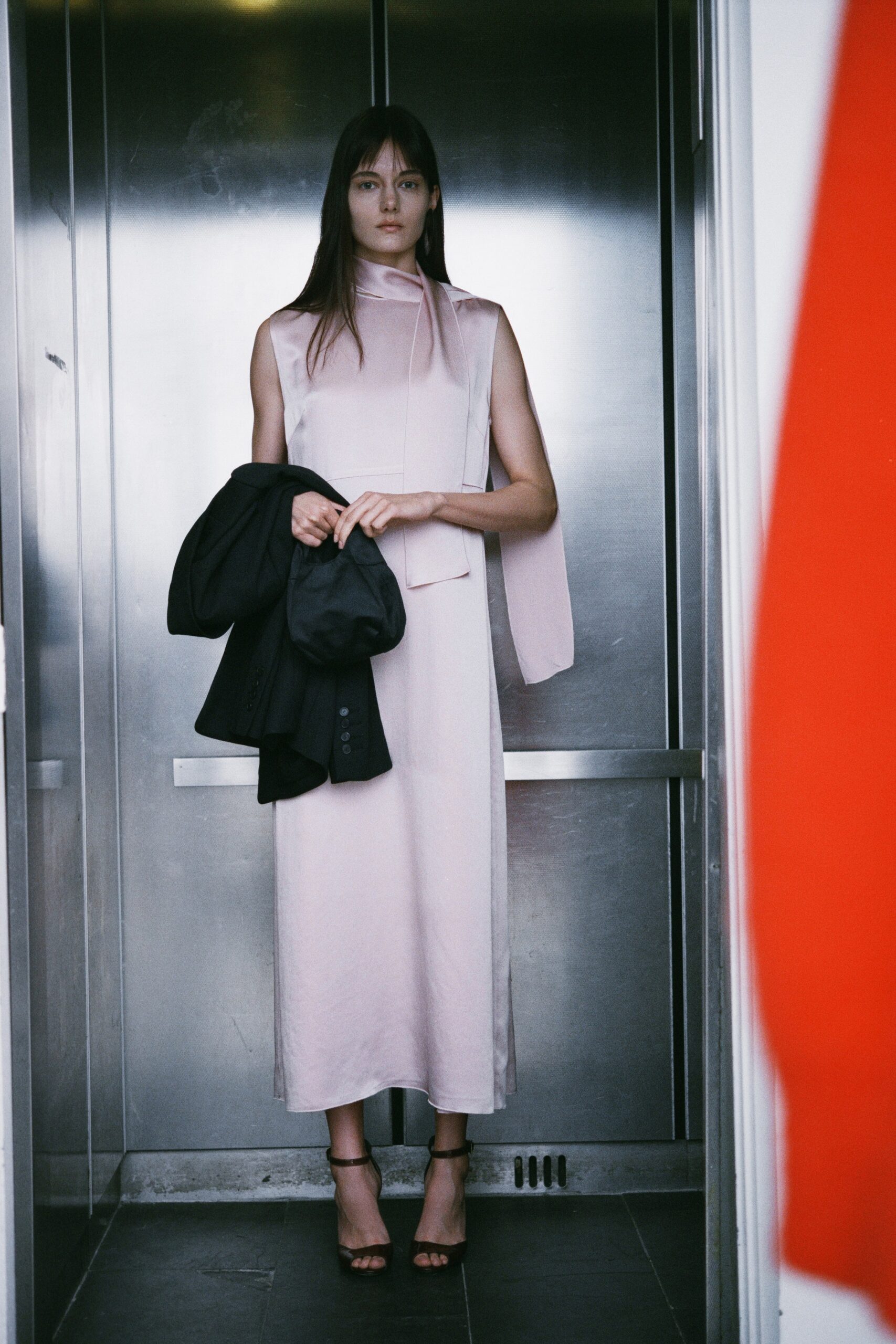 A fitted pink silk dress with a sleeveless design and asymmetric details.
