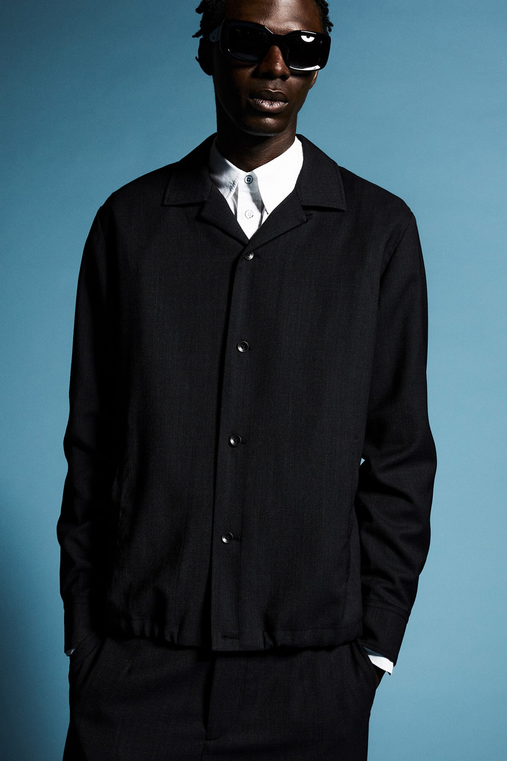 A relaxed black cotton jacket with long sleeves and a collared design, featuring button details.