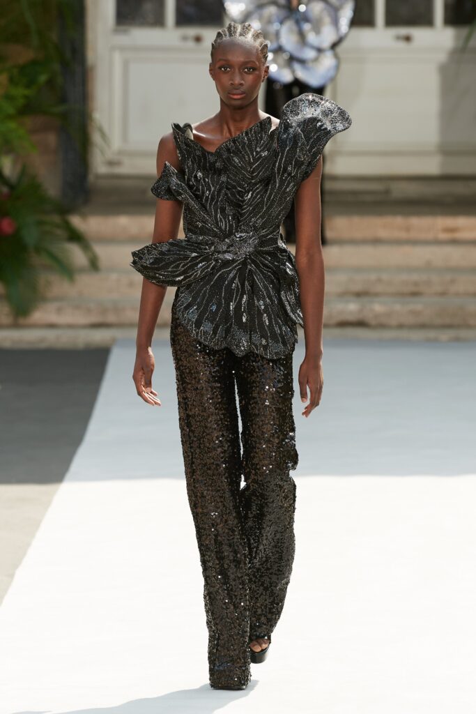 A fitted black sequin top with short sleeves and high-neck paired with fitted pants.