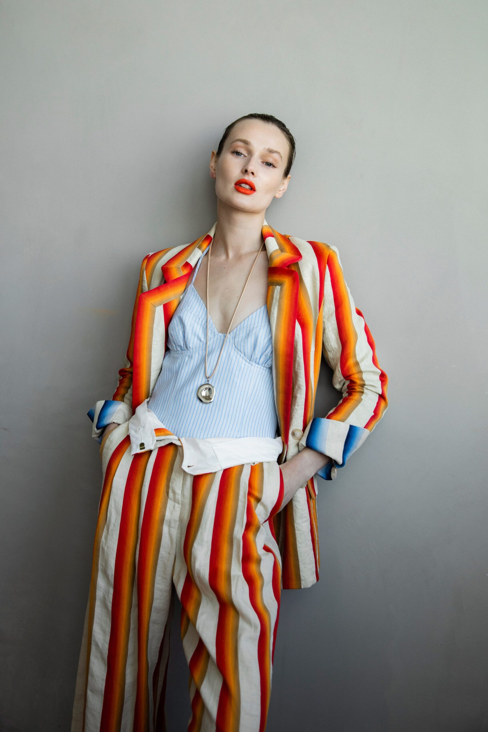 A fitted multicolor striped blazer paired with matching pants, featuring a collared neckline.