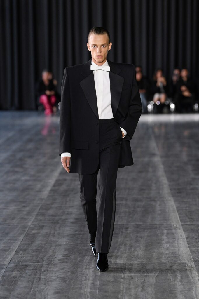 A tailored black wool blazer with long sleeves and a collared neckline paired with matching pants.
