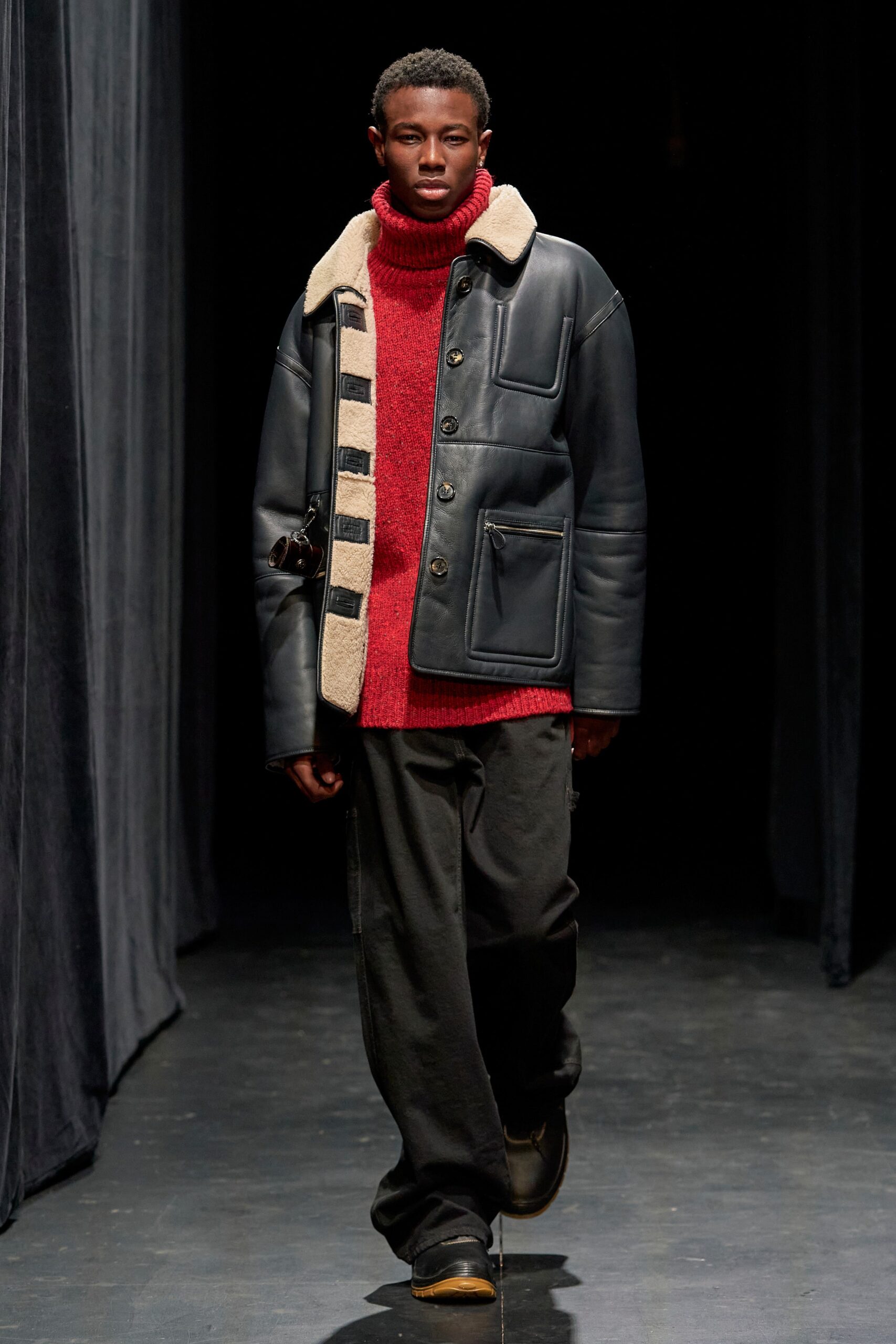 A relaxed black leather jacket paired with a long-sleeve red wool sweater.