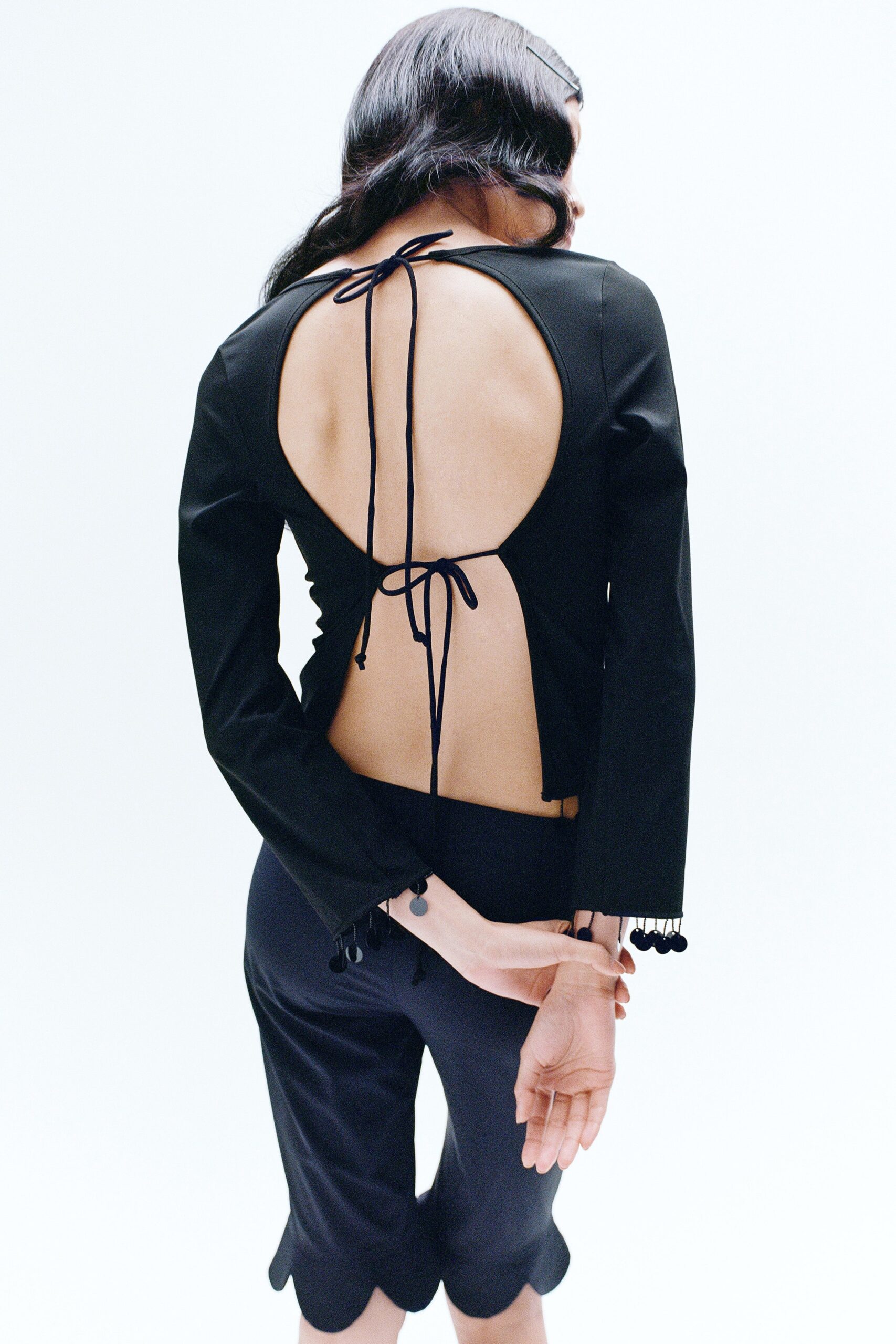 A fitted black long-sleeve top with a backless design paired with fitted pants.