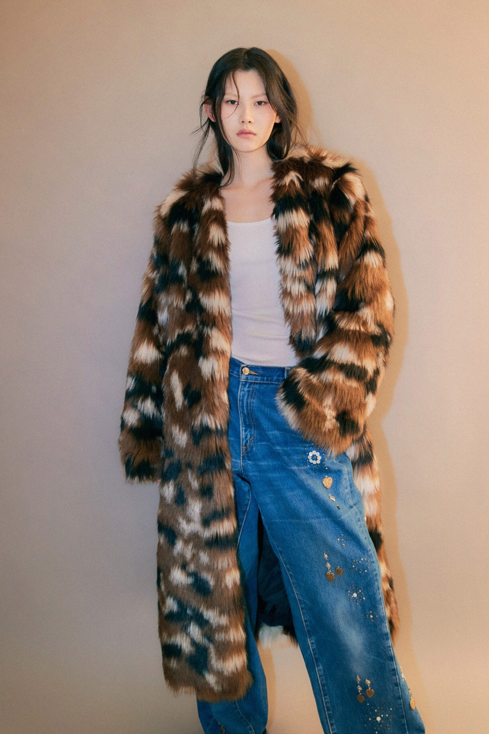 A relaxed brown fur coat with a printed design paired with blue denim pants.