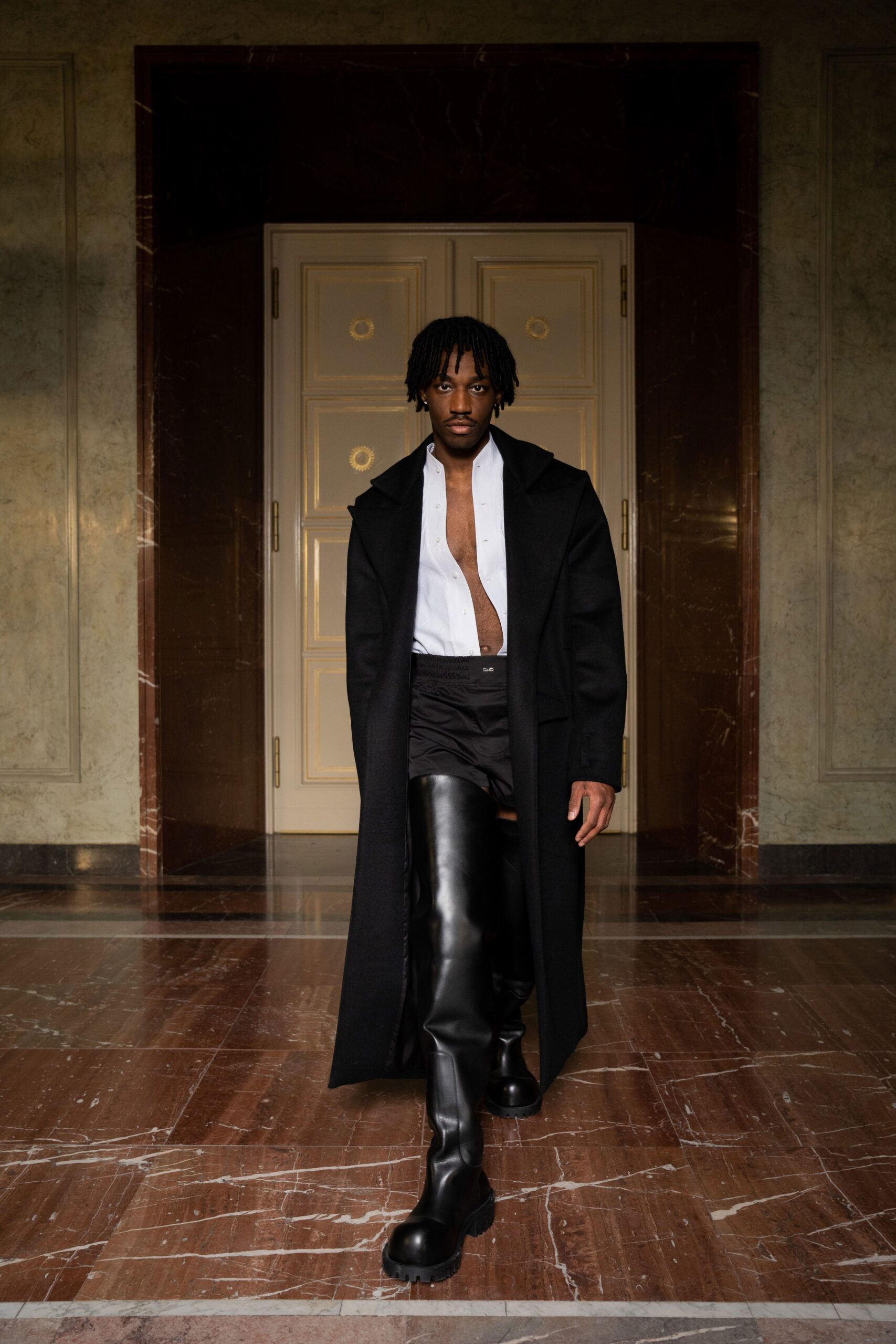 A fitted black leather coat paired with straight-leg pants, featuring a collared neckline.