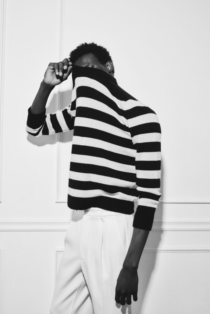 A fitted black and white striped sweater paired with tailored pants.