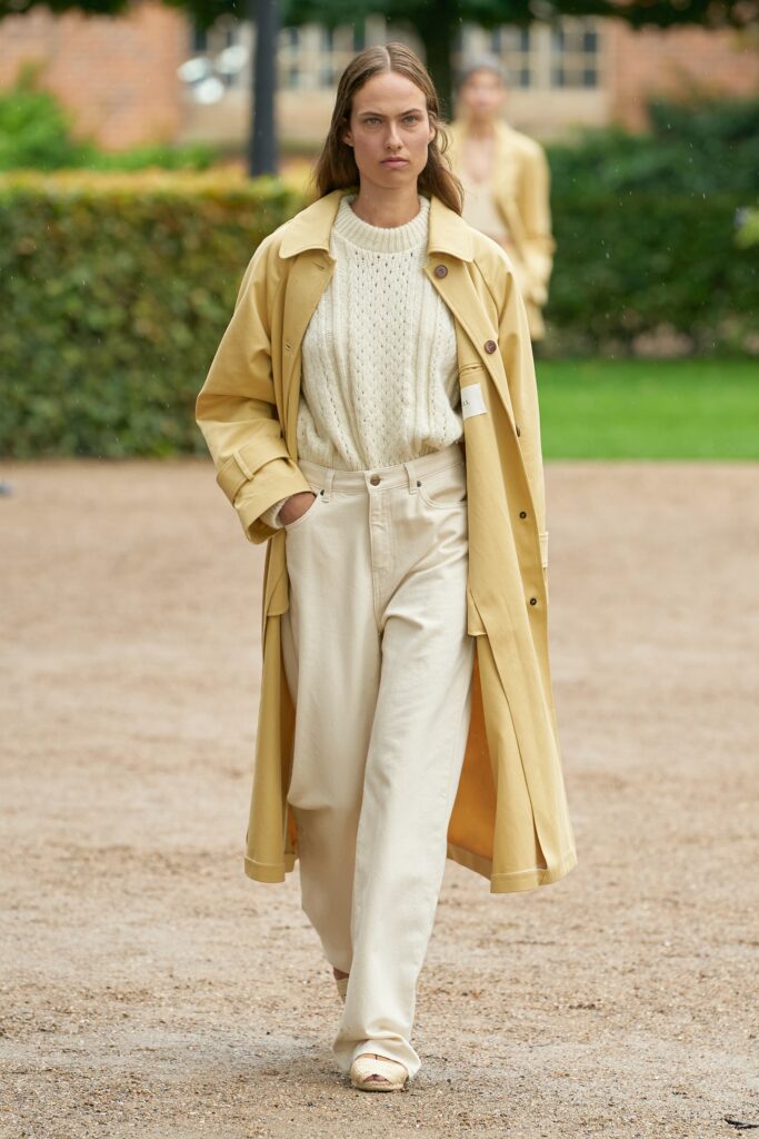 A relaxed yellow coat paired with a long-sleeve knit white sweater.