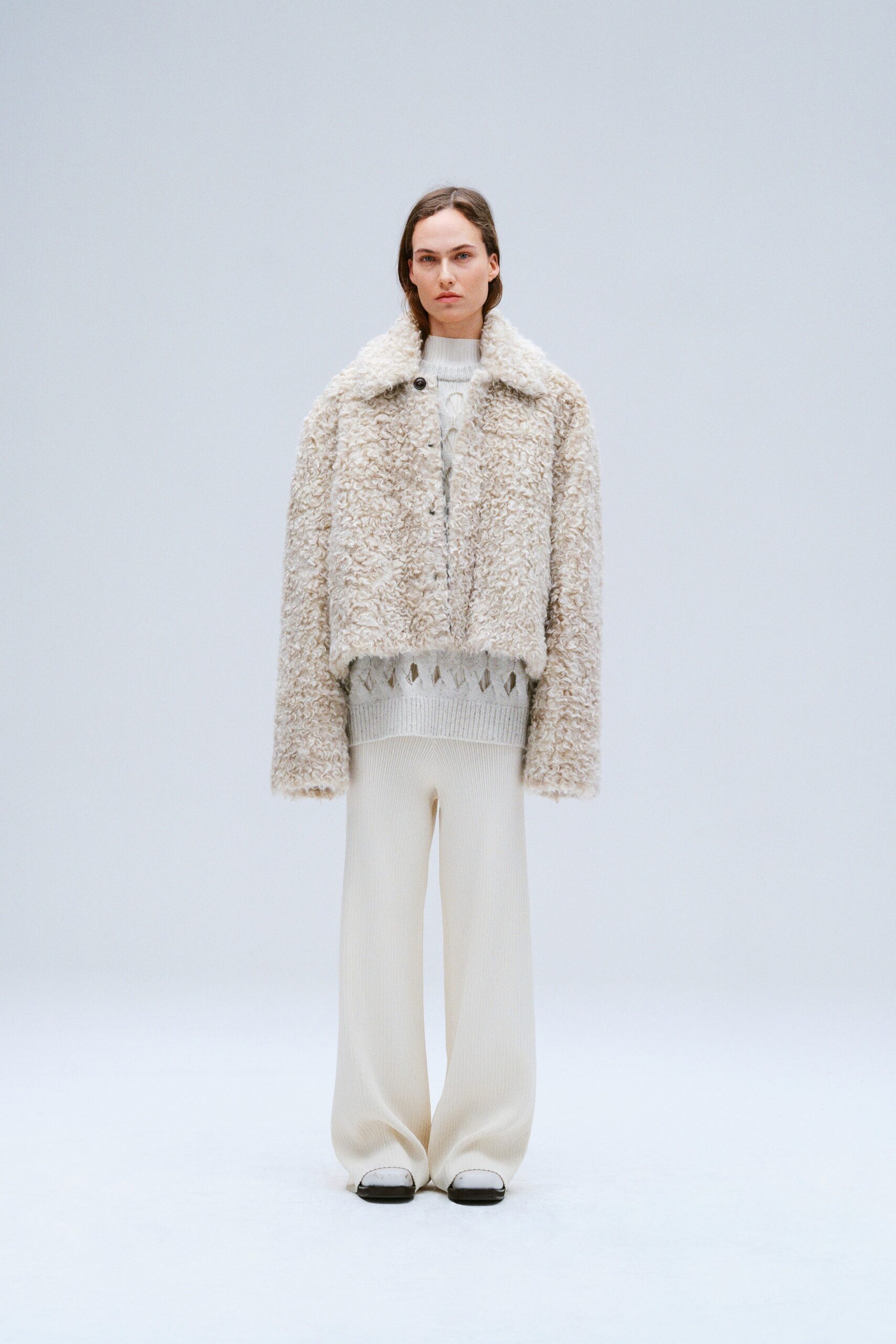 A relaxed beige fur jacket paired with wide-leg knit pants for a stylish look.