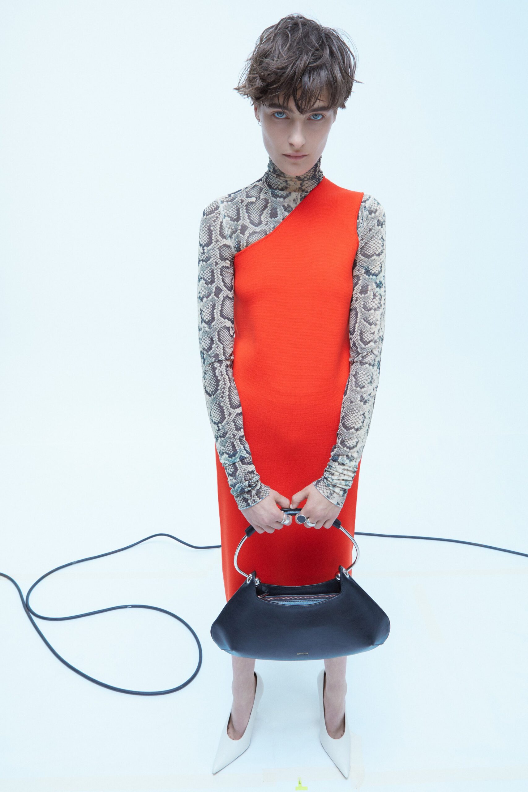 A fitted red dress with an asymmetric design, featuring a long-sleeve high-neck top.