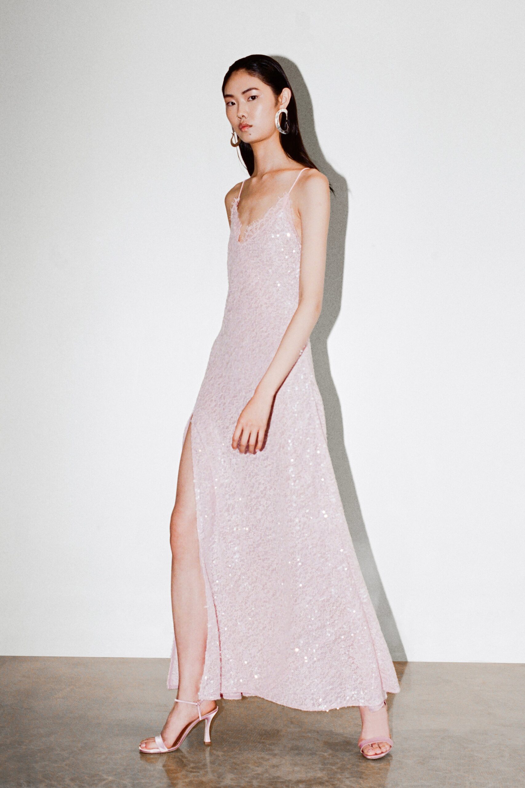 A fitted pink sequin dress with a sleeveless design, V-neckline, and a side slit.