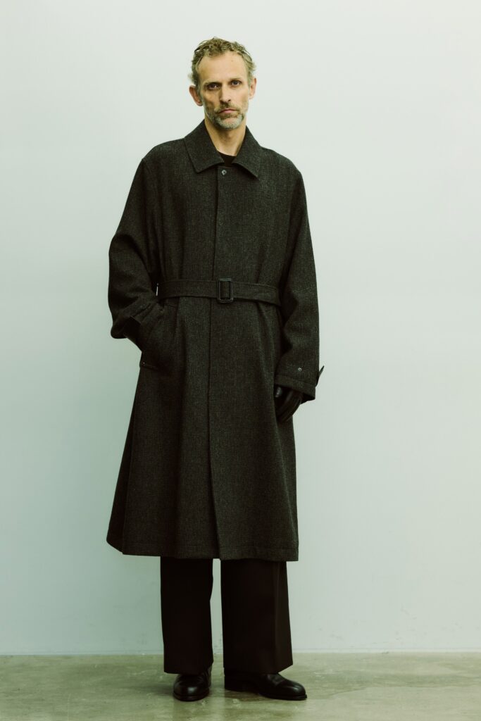 A tailored black wool coat with a belt, paired with black pants for a sophisticated look.