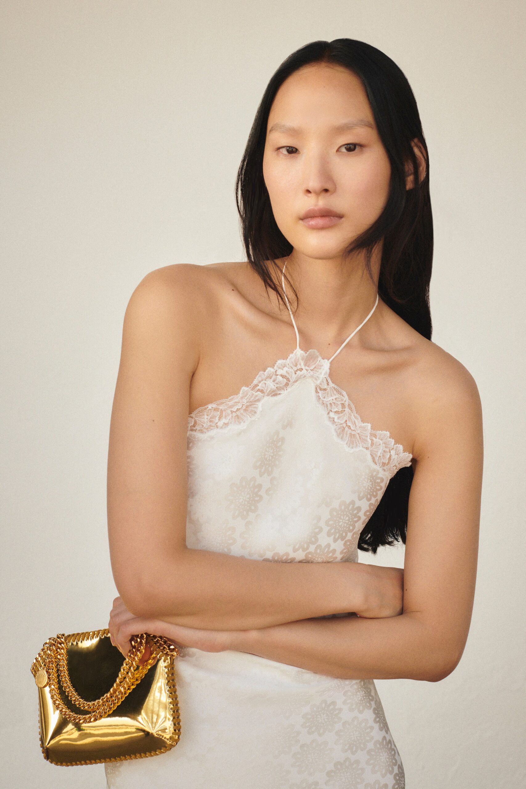 A fitted white silk dress with a sleeveless design and embroidered details.