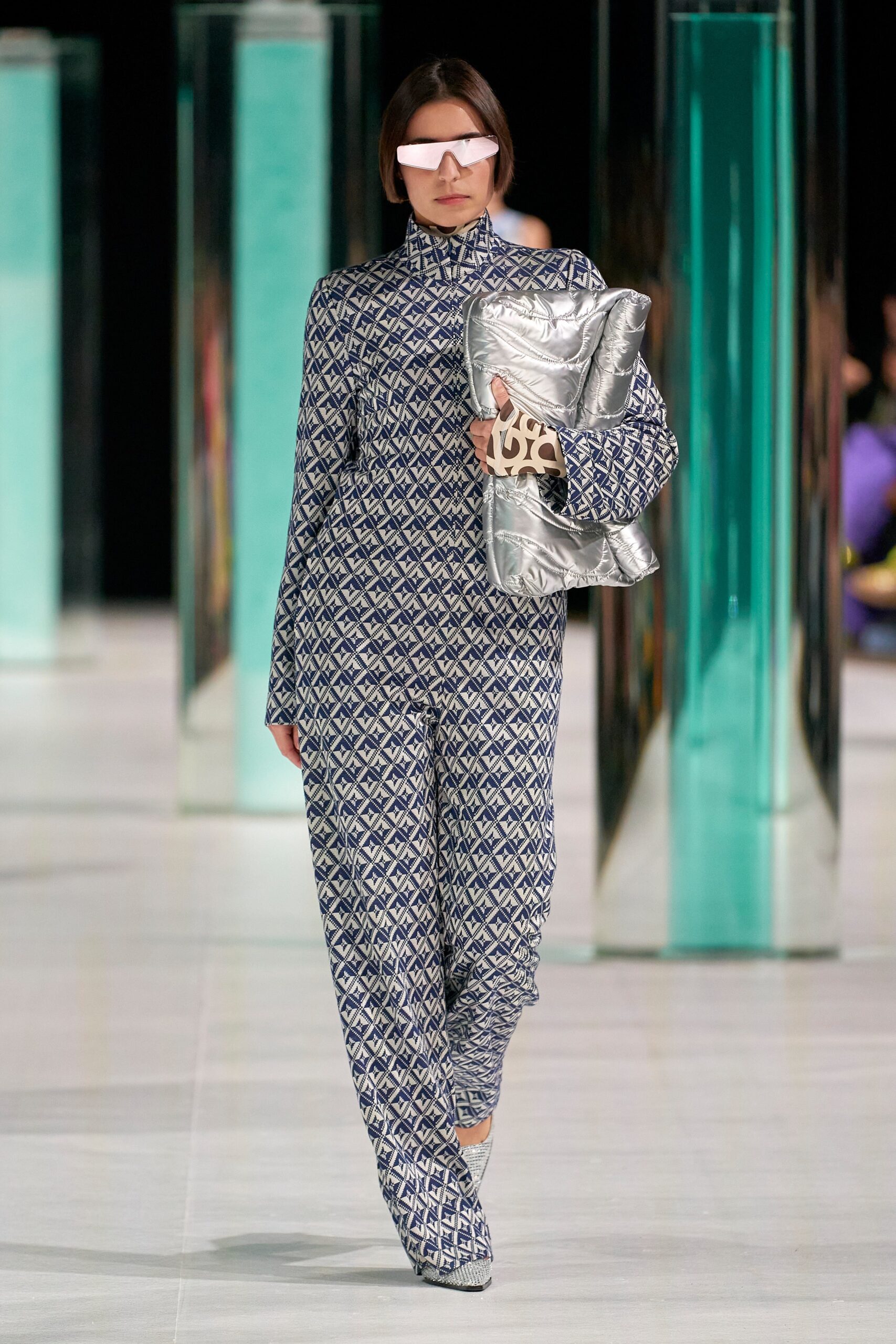 A fitted blue printed jumpsuit with long sleeves and a high neckline.