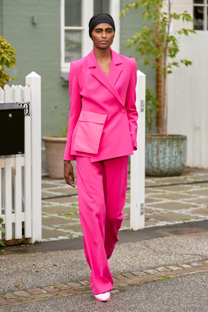 A fitted pink blazer with matching pants, featuring a collared design and straight-leg silhouette.
