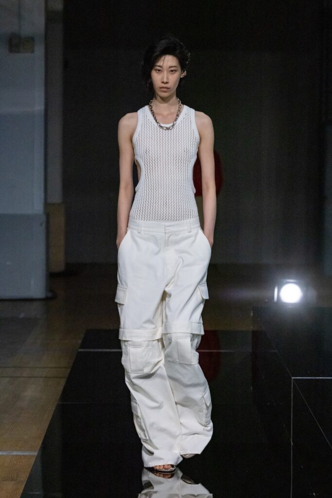 A relaxed white sleeveless top paired with loose-fitting pants, creating a modern and casual look.