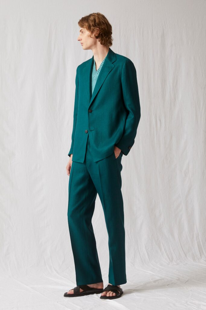 A tailored teal suit with long sleeves and a collared design, featuring straight-leg trousers.