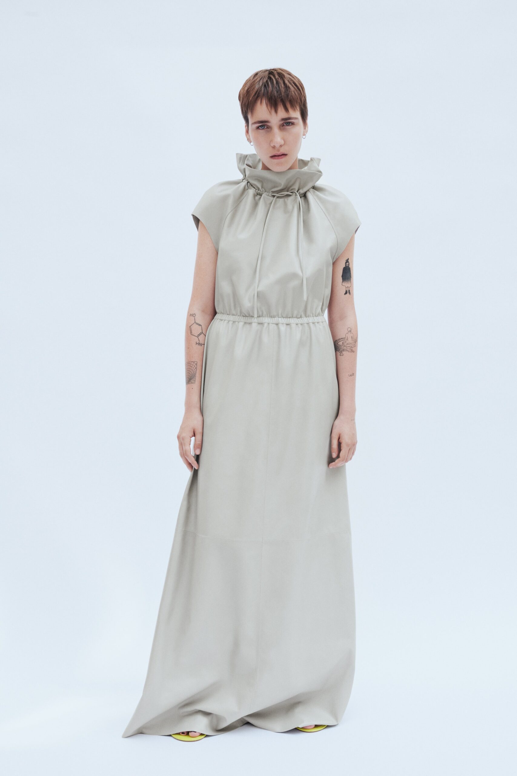 A relaxed beige sleeveless dress with a high neckline and a maxi silhouette.