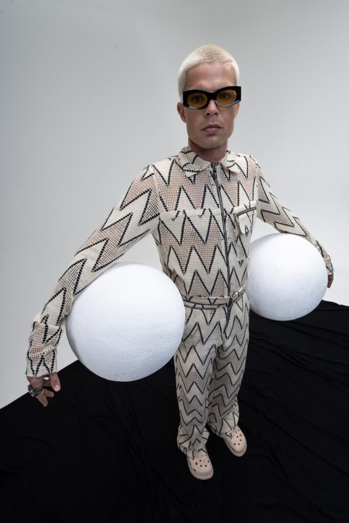 A fitted beige jumpsuit with long sleeves, a collared neckline, and a printed design.