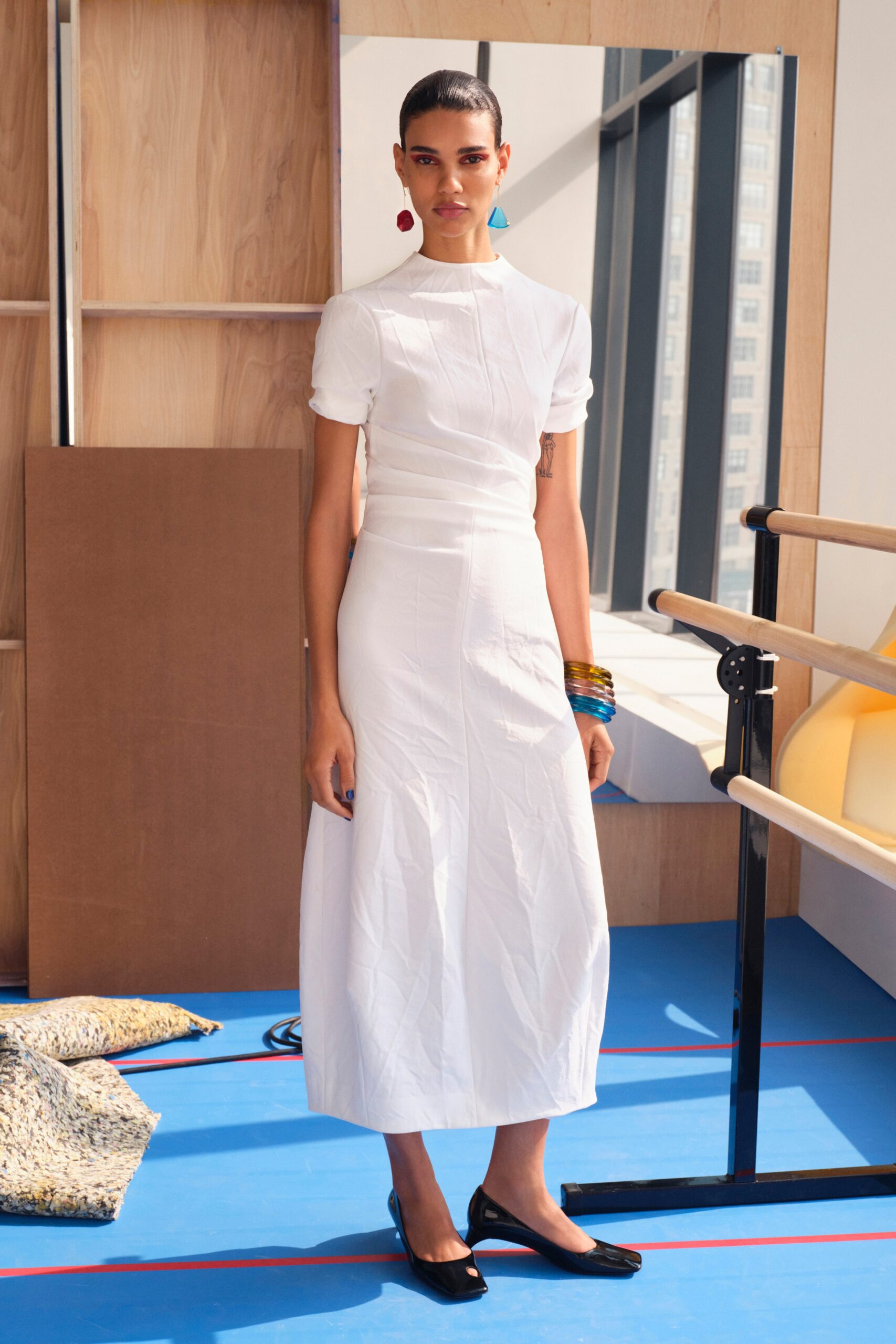 A fitted white cotton dress with short sleeves and a high neckline in a midi length.