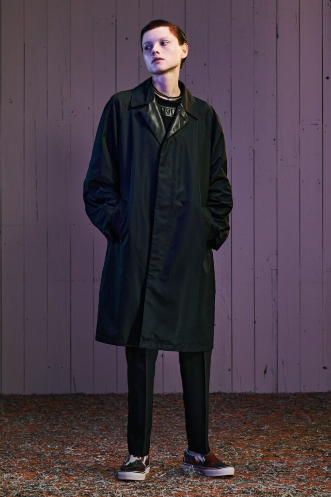 A relaxed black coat with long sleeves and a collared neckline paired with straight-leg pants.