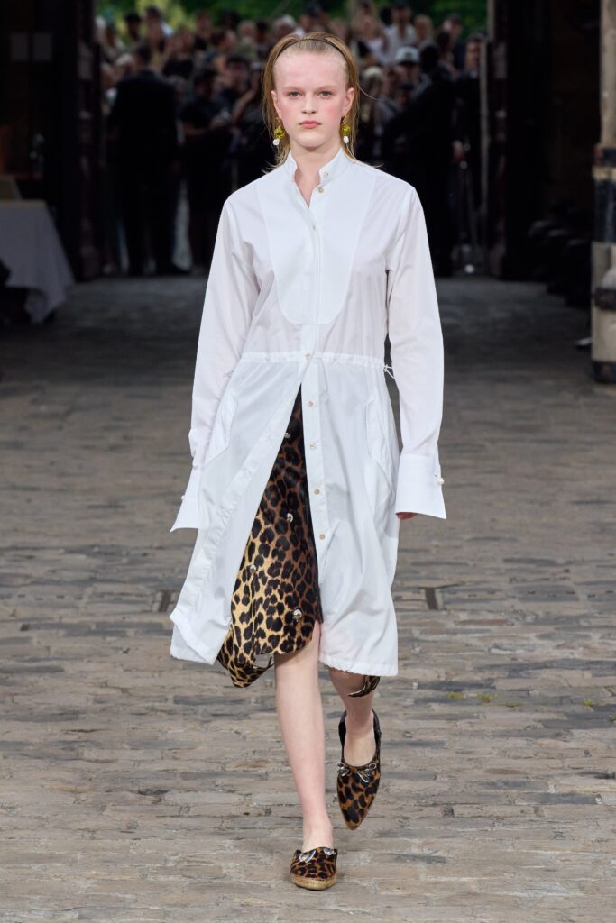 A relaxed white cotton shirt-dress with long sleeves, a collared neckline, and animal-print detailing.