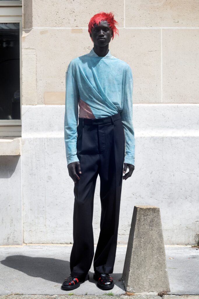 A relaxed blue cotton long-sleeve shirt with an asymmetric design paired with black pants.