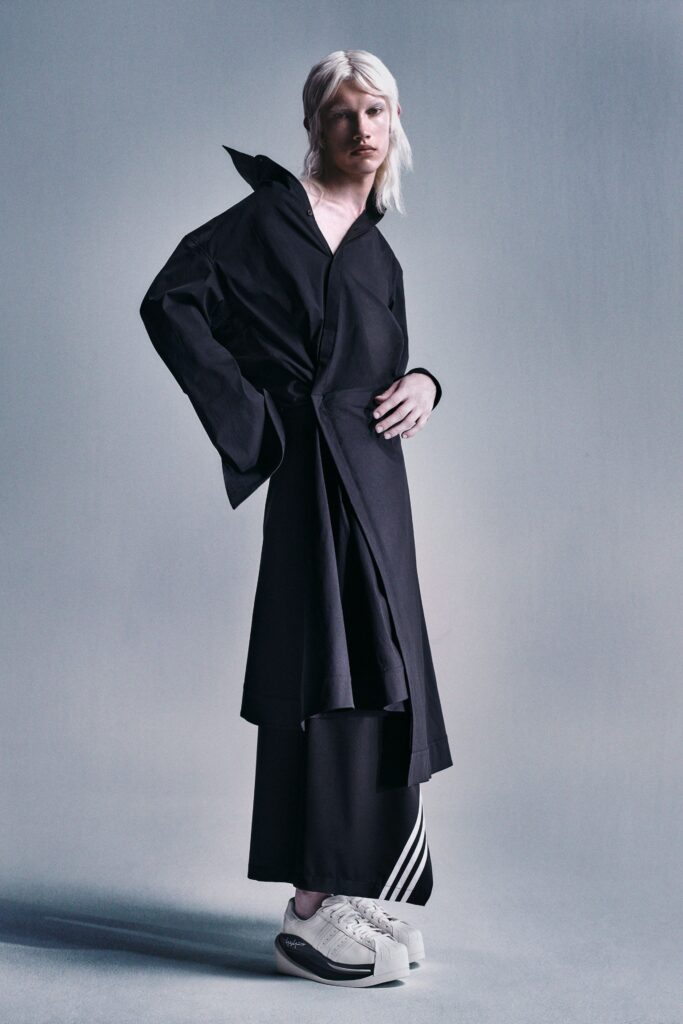A relaxed black coat with a collared neckline and asymmetric design paired with black pants.