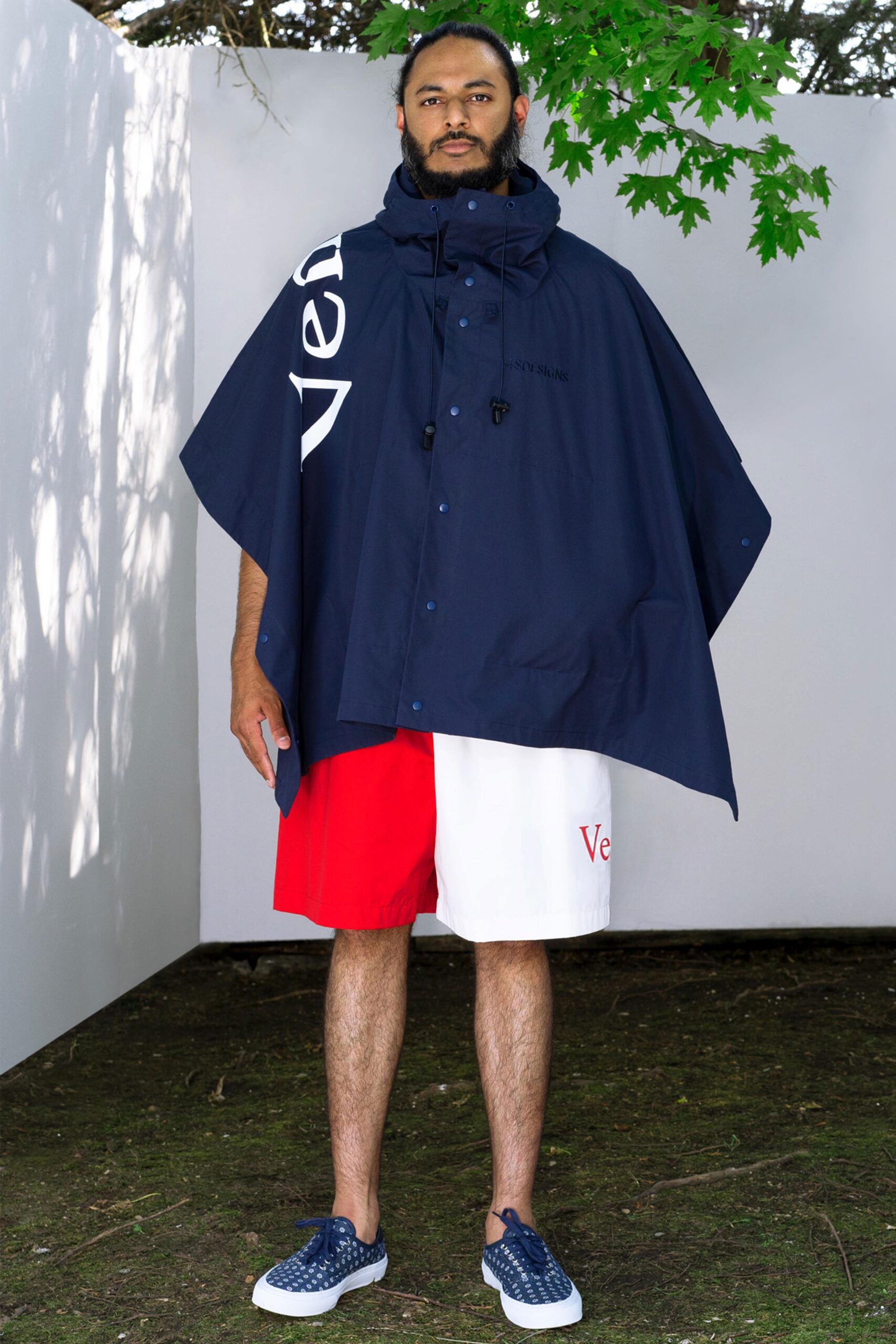 A relaxed navy poncho paired with color-blocked white and red shorts.