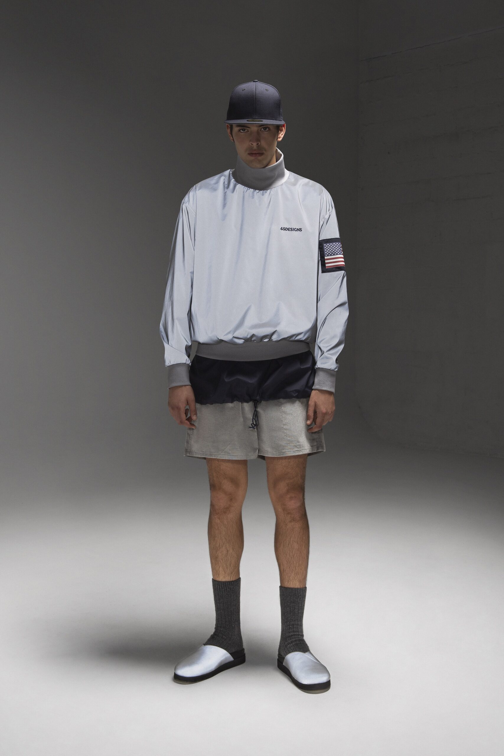 A relaxed gray long-sleeve top with a zippered detail, paired with black shorts.