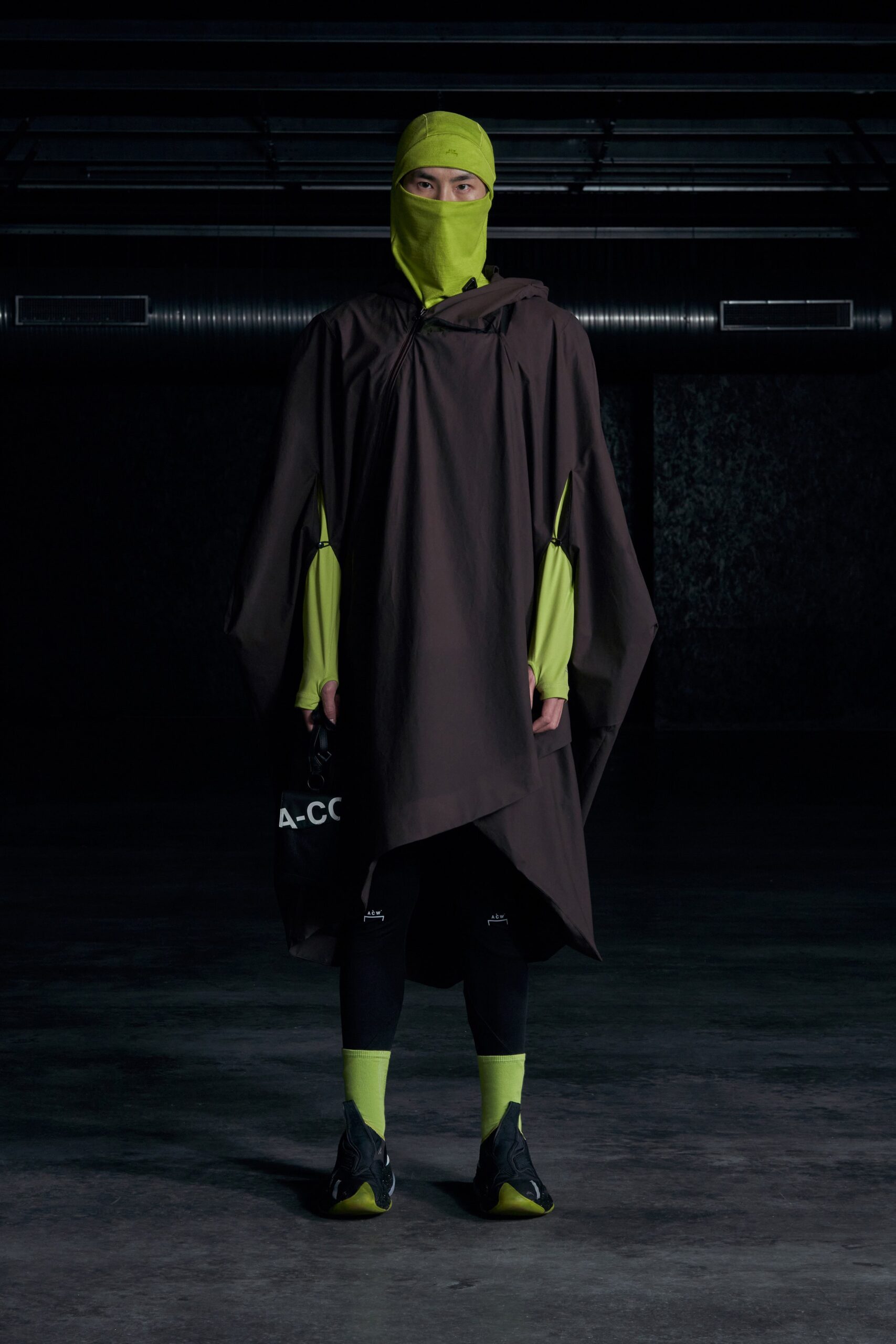A relaxed brown cotton poncho paired with neon green leggings, featuring an asymmetric design.