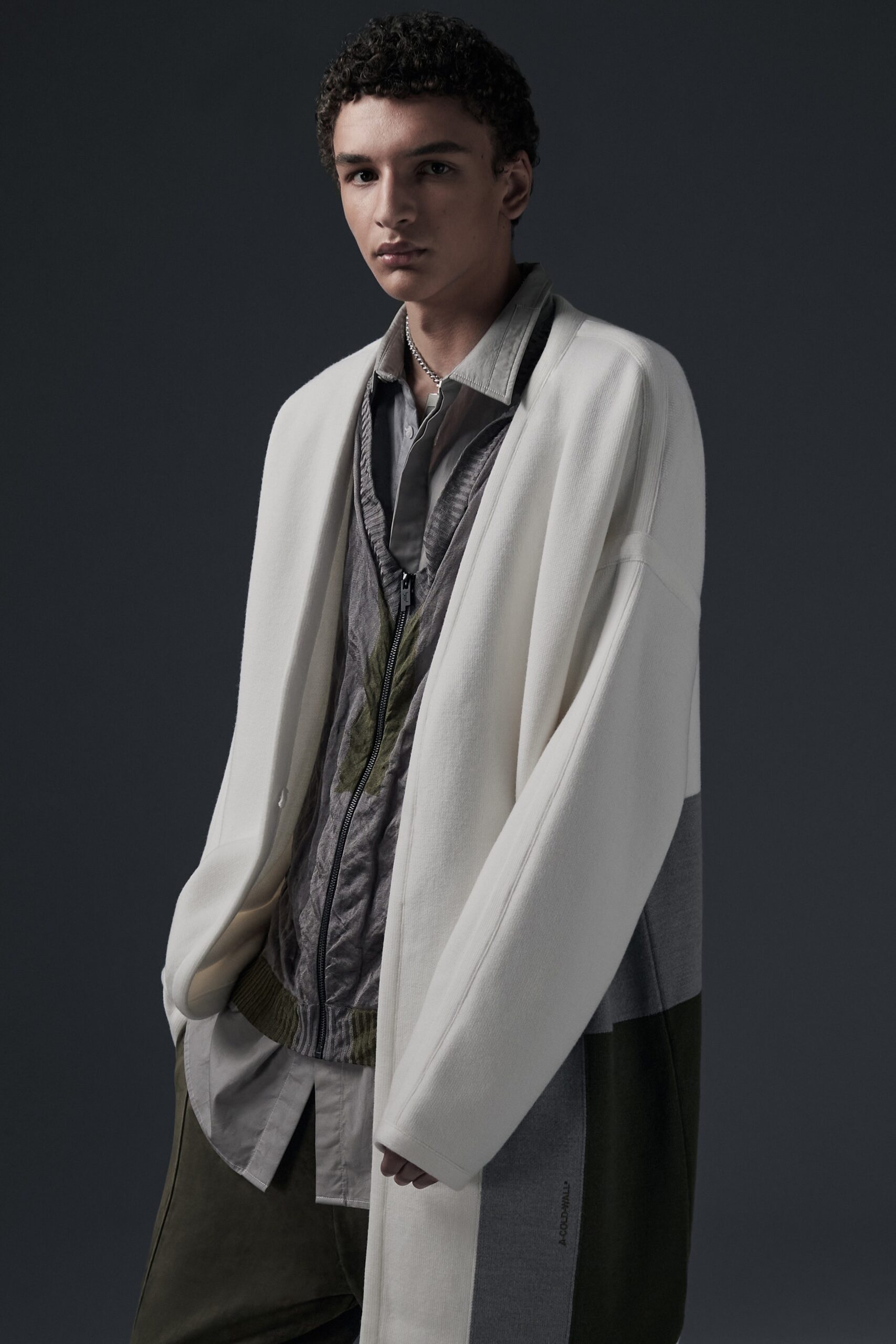 This oversized coat features a striking color-blocked design, blending shades of white, gray, and green. The long sleeves and collared neckline create a relaxed silhouette, while the layered effect adds depth and visual interest.