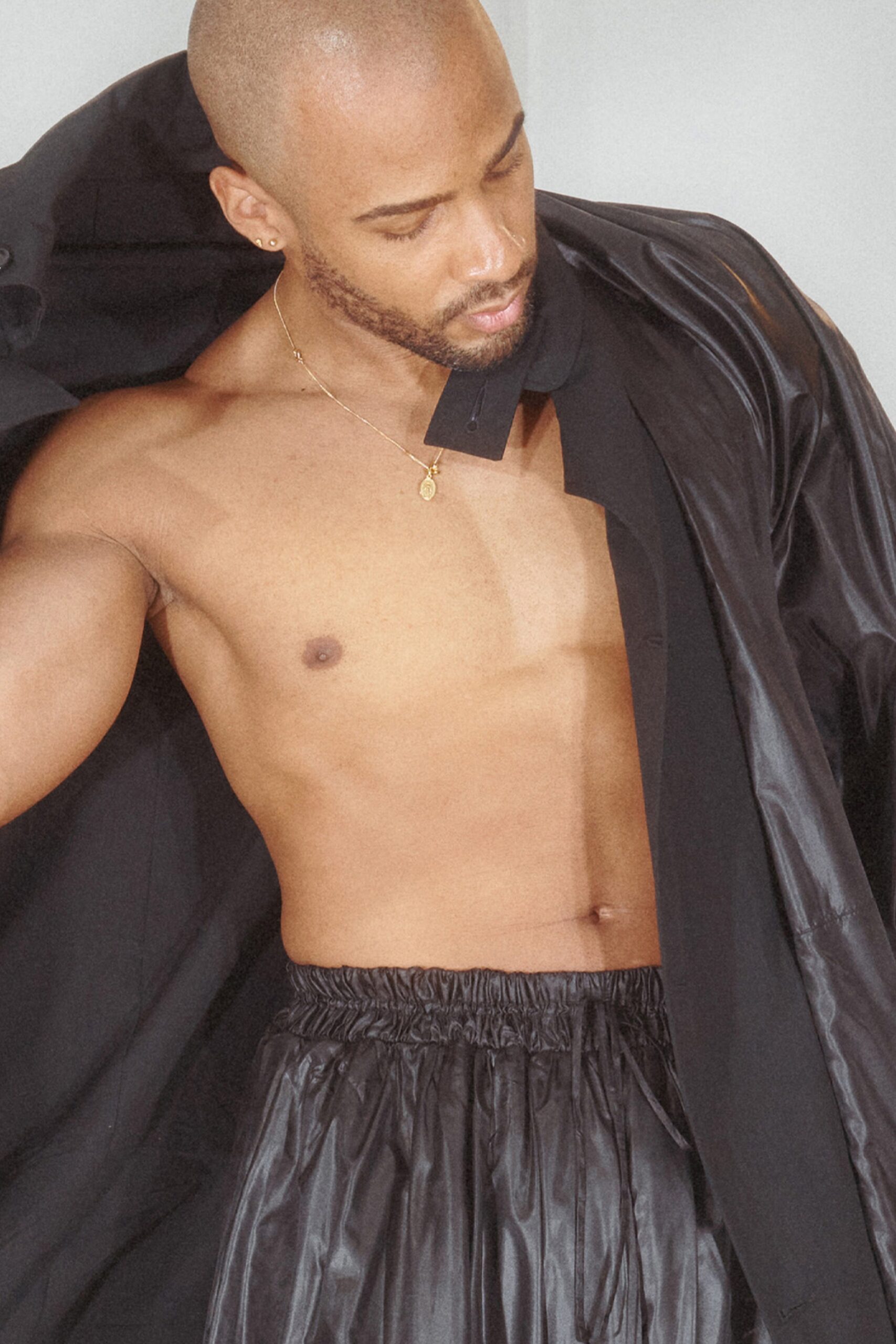 A relaxed black leather jacket features a classic collared design with a zippered front, exuding an effortlessly cool vibe. Paired with pleated black pants, the ensemble offers a striking contrast in texture and structure, creating a modern silhouette that commands attention.